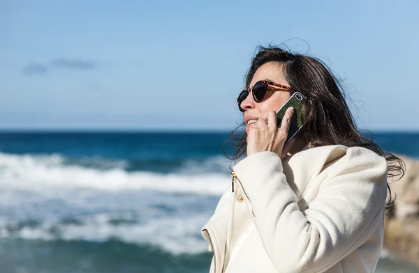 Attraktive Frau posiert am Meer und telefoniert — Stockfoto