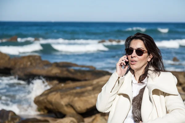 Attractive woman on seashore talking on the phone — Stock Photo, Image