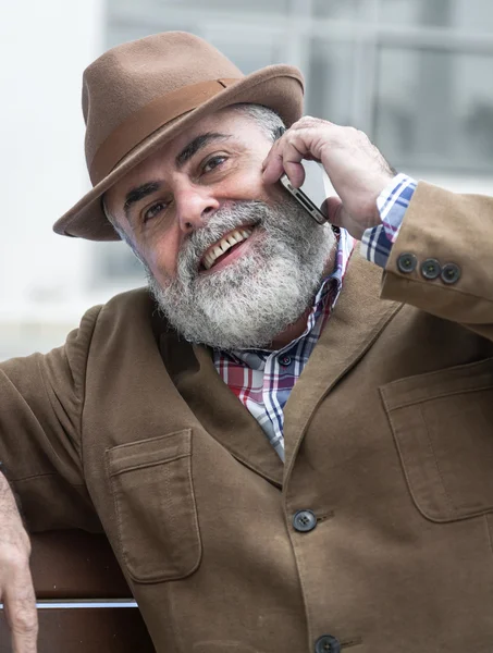 ชายแก่ที่น่าสนใจมีเคราและหมวกพูดคุยทางโทรศัพท์ — ภาพถ่ายสต็อก