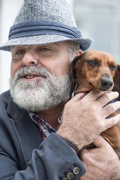 Привлекательный старик с бородой и шляпой и собачьей повязкой. — стоковое фото