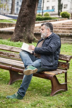 Çekici sakallı adam parkta okuma
