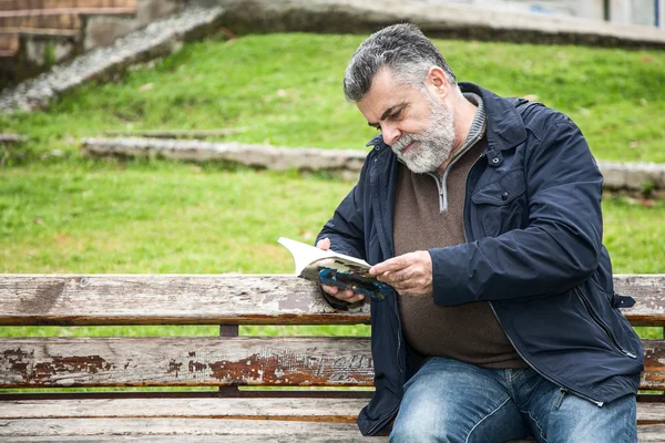 Homem barbudo atraente lendo em um parque — Fotografia de Stock