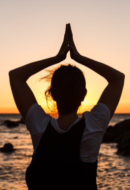 gün batımında sahilde Yoga uygulamak siluet genç kadın.