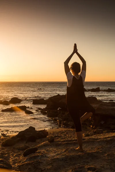 Silhouette young woman practicing yoga on the beach at sunset. — Stock Photo, Image