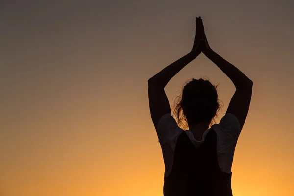 Silhouette young woman practicing yoga on the beach at sunset. — Stock Photo, Image