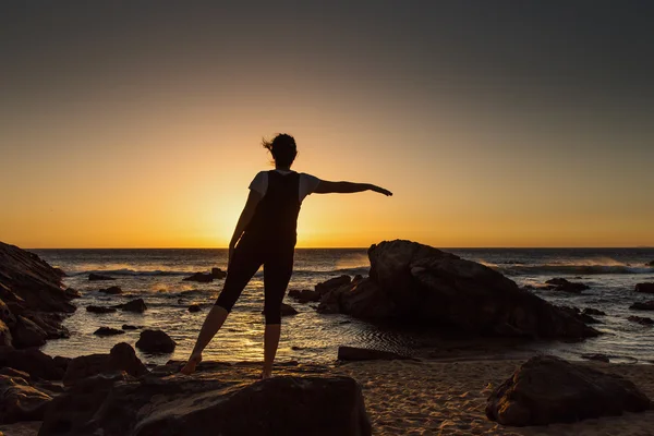 Silhouette giovane donna che pratica yoga sulla spiaggia al tramonto . — Foto Stock