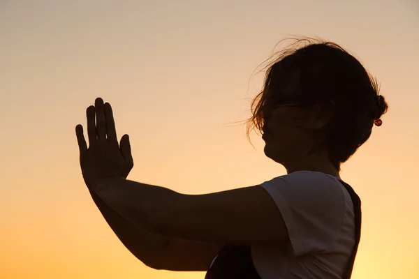 Silhouette young woman practicing yoga on the beach at sunset. — Stock Photo, Image