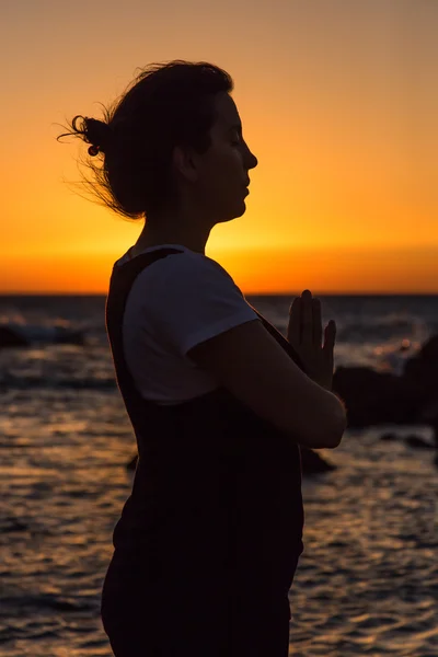 Silhouette giovane donna che pratica yoga sulla spiaggia al tramonto . — Foto Stock