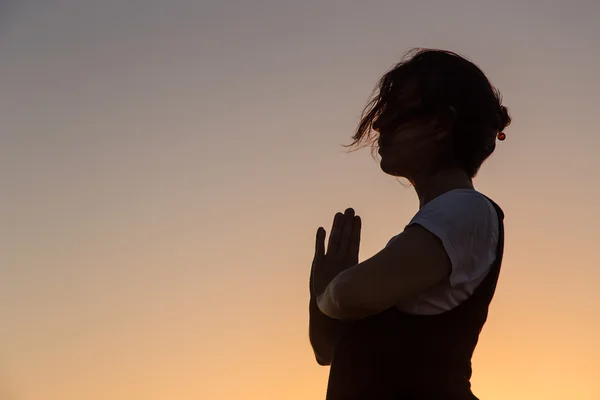 Silhouette young woman practicing yoga on the beach at sunset. — Stock Photo, Image