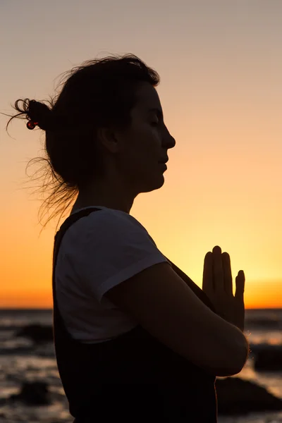 Silhouette giovane donna che pratica yoga sulla spiaggia al tramonto . — Foto Stock