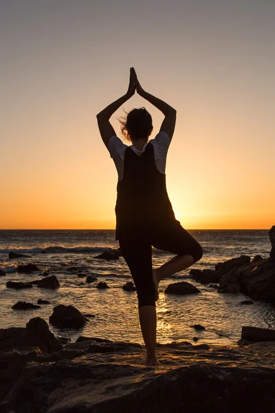 Silhouette junge Frau übt Yoga am Strand bei Sonnenuntergang. — Stockfoto