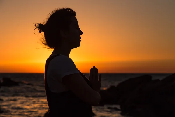 Silhouette giovane donna che pratica yoga sulla spiaggia al tramonto . — Foto Stock