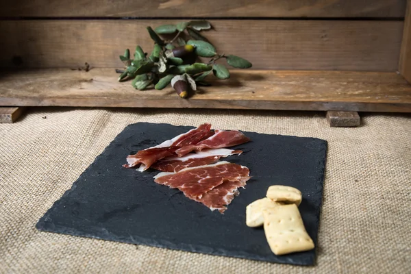 Prosciutto su tavola di legno — Foto Stock