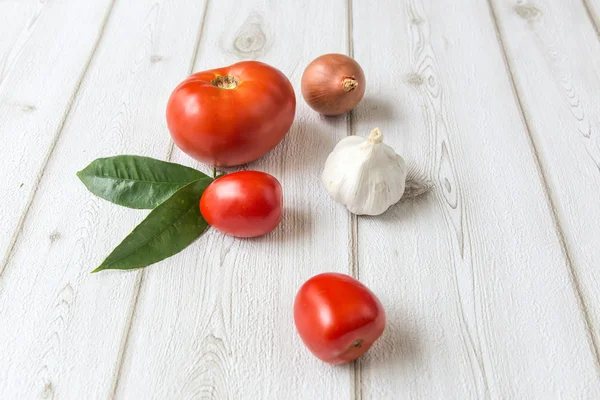 Fresh tomatoes and garlic and onion on wooden board — Stock Photo, Image