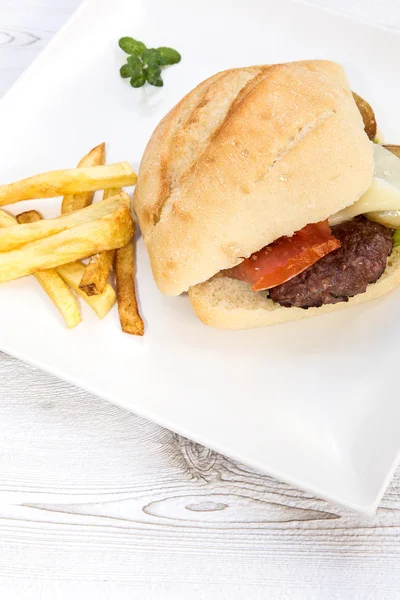 Burger med ost, tomat, salat og chips – stockfoto