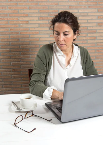 Vrouw achter laptop met koffiekopje — Stockfoto