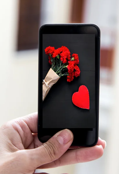 Smartphone main tenant avec image de bouquet d'oeillets rouges — Photo