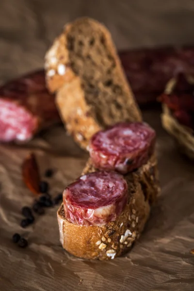 Pezzi di salsiccia con pane su carta — Foto Stock