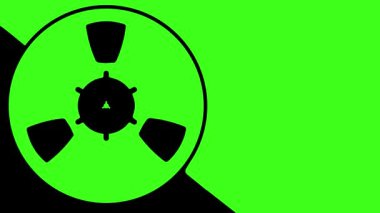 Yeşil arkaplan üzerinde dönen tipik bir manyetik kayıt bandı makarası