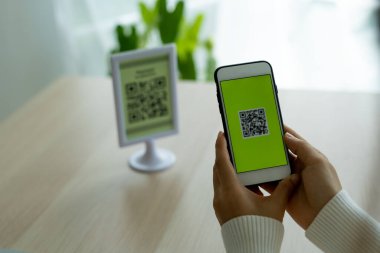 Kadının eli, yemek menüsünü seçmek için QR kodunu tarıyor. İndirim almak ya da yemek için ödeme yapmak ve restoranda ya da kafede nakit olmadan internet üzerinden para aktarmak için tarama yapın.