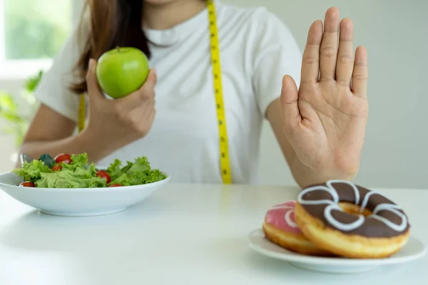Kadınlar abur cuburu veya donut gibi sağlıksız yiyecekleri reddeder ve yeşil elma ve salata gibi sağlıklı yiyecekleri seçerler. Oruç ve sağlık kavramı.