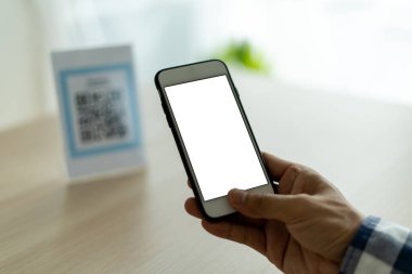 Adamın eli QR kodunu taramak için cep telefonu kullanıyor. Adam restoranda ya da kafede yemek ve içecek indirimi için tarama yapıyor. Nakit ödemeden ödeyin.