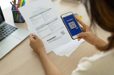 El, QR kodunu taramak için telefonu kullanıyor ve ofiste elektrik faturalarını ödemekten indirim alıyor.