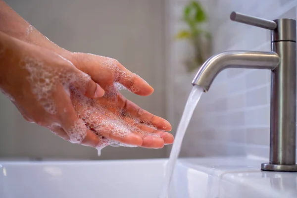 Women wash their hands with soap and water from the tap in the bathroom. Good hygiene and hand washing, prevent germs