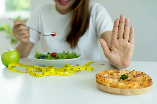 Healthy women use hands to push plates onto pizza. Skinny women choose to eat a healthy diet with fiber and high vitamins such as vegetables and apples. No eating starchy and trans fat foods