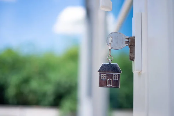 Yeni bir evin kilidini açmanın anahtarı kapıya takılı. Kiralık ev kavramı, satın alma veya satma.