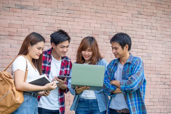 A group of Asian students are standing, talking, talking. Men and women students are talking about a report or homework in their free time or after school.