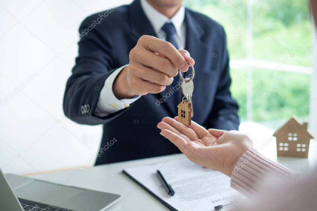 The employee gave the house keys to the customer for mortgage or purchase. Real Estate Agents and Clients Discussing Mortgage Contracts