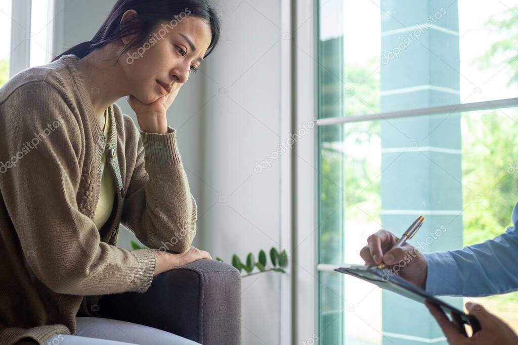 Female patients sitting and discussing mental illness with the psychiatrist. The doctor's hand is recording the symptoms and ready for treatment. Psychiatrist concept, depression
