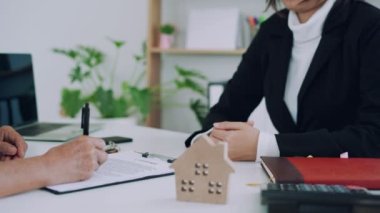 Satış temsilcisi, satış anlaşması tamamlandıktan sonra yeni ev sahiplerine el sıkışıyor ve anahtarları teslim ediyor. Konsept sözleşmesi.