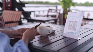 Kadın, kafeteryada nakit olmadan dijital ödeme yapmak için akıllı telefon kullanarak QR kodunu tarıyor. Menüyü ve siparişi seçin ve indirimi toplayın. Cüzdan, teknoloji, online ödeme, kredi kartı, banka uygulaması, tarama