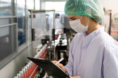 Bir teknoloji uzmanı ya da müfettiş yiyecek fabrikası üretim hattının siparişlerini doğrulamak için panoya not alıyor. Üretim kontrol çalışanları