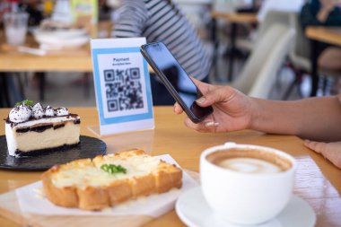 Kadınların elleri yemek menüsünü seçmek için QR kodunu tarıyor. İndirim için tarama yap ya da yiyecek için ödeme yap. Para transferi için telefon kullanma ya da nakit olmadan internet üzerinden para ödeme kavramı..