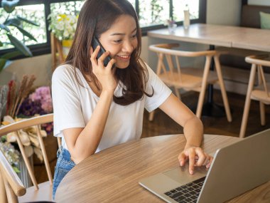 Yakışıklı Asyalı kadınlar yabancı arkadaşlarıyla iletişim kurmak için internete bağlanmak için bilgisayar kullanırlar. Mutlu ve rahat bir kadın kanepede oturuyor. Çalışan kadın ve serbest çalışan danışman