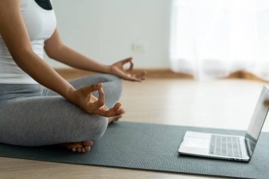 Egzersiz kıyafetleri giyen kadınlar yoga poziyonu alıp evde sakin sakin oturuyorlar. Kadınlar yogayı internetten tabletle öğreniyor. Sağlıklı yaşam tarzı fikirleri