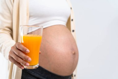 28 haftalık hamile bir kadın portakal suyu tutuyor ve doğmamış çocuğunun sağlıklı gelişimi ve büyümesi için besleyici bir diyet seçiyor..