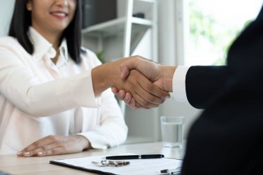 Emlakçı, konutun satışı ya da sigortası için yasal bir anlaşma yaptıktan sonra müşteriyle tokalaşır. Ev ticareti pazarlıklarında başarı. Konut kredisi