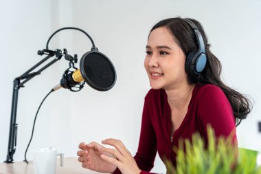 Parlak Asyalı kadınlar mikrofon ve bilgisayar kamerasıyla podcast kaydediyor. Ev stüdyosunda çalışan genç bir kadın. Yayın stüdyosu