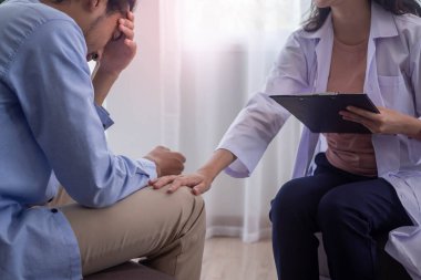 Hasta stresli ve psikotik semptomları var. Bir doktor, sorunlu ya da zihinsel engelli bir hastaya destek olmak için dizlerini tutar. Doktor tedaviyi kaydetmek için elinde bir dosya tutuyor..