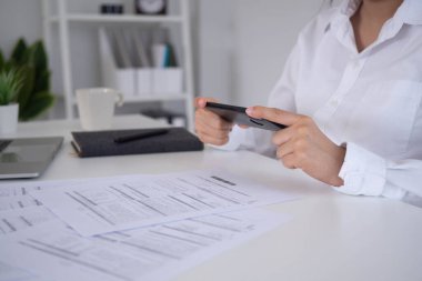 Bir işadamı internet üzerinden internete bağlanıp online ödeme uygulamalarına erişmek için akıllı telefon kullanarak barkod taraması yapıyor..