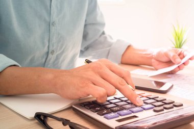 Kâhya hesap makinesine basıyor fatura ile ödenmesi gereken çeşitli masrafları hesaplıyor. Birçok fatura tutulup masaya kondu