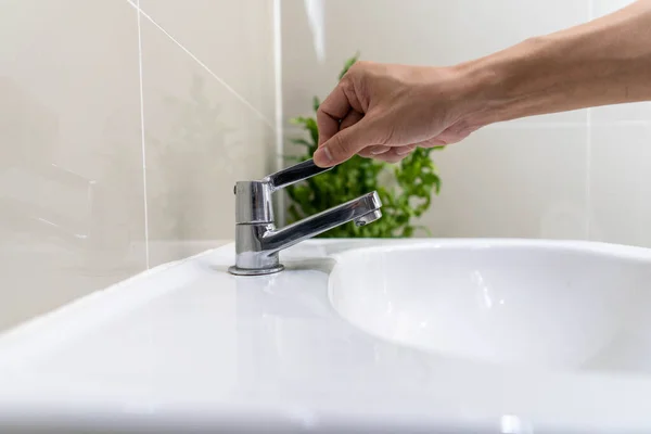 Banyodaki musluk ve akan su. İnsanlar suyu kapatmaya devam ediyor. Enerji tasarrufu ve çevreyi korumak için..