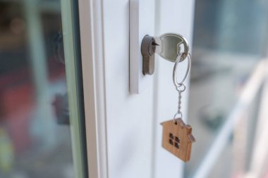 Landlord key for unlocking house is plugged into the door. Second hand house for rent and sale. keychain is blowing in the wind. mortgage for new home, buy, sell, renovate, investment, owner, estat