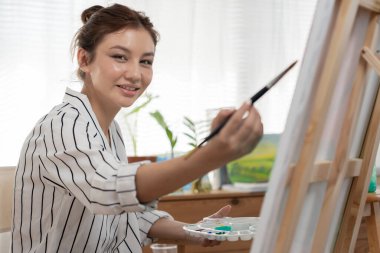 Portrait female artist girl use paintbrush in abstract art for create masterpiece. painter paint with watercolors or oil in studio house. beautiful woman enjoy painting as hobby. work recreation