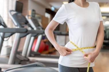 Diyet ve diyet. Güzel, ince kadın vücut ölçüsü fitness için şerit kullanır. Spor elbiseli bir kadın sağlıklı yaşam için kilo verme hedefine, zayıflığa, ince belliye, beslenme uzmanına ulaşır..