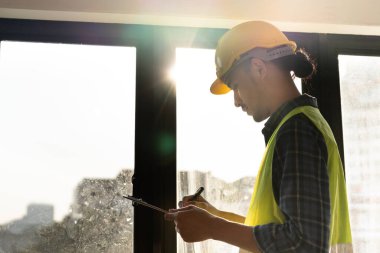 inspector or engineer is inspecting construction and quality assurance new house using a checklist. Engineers or architects or contactor work to build the house before handing it over to the homeowner